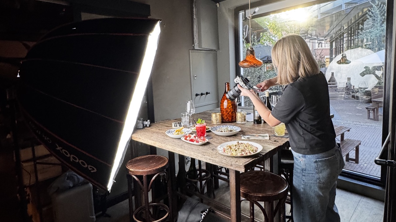 Pien styling a table of dishes on a lit set during a restaurant food shoot